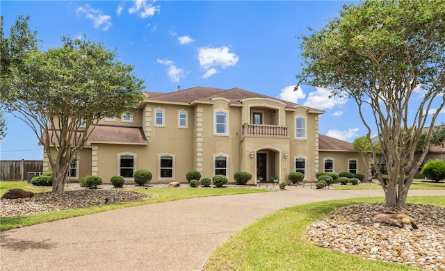 6001 King Trl, Corpus Christi, TX 78414 - mediterranean / spanish-style home featuring a balcony, stucco siding, curved driveway, and a front lawn