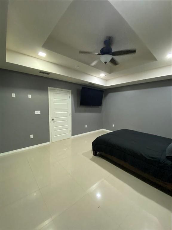 bedroom with tile patterned floors, ceiling fan, and a raised ceiling