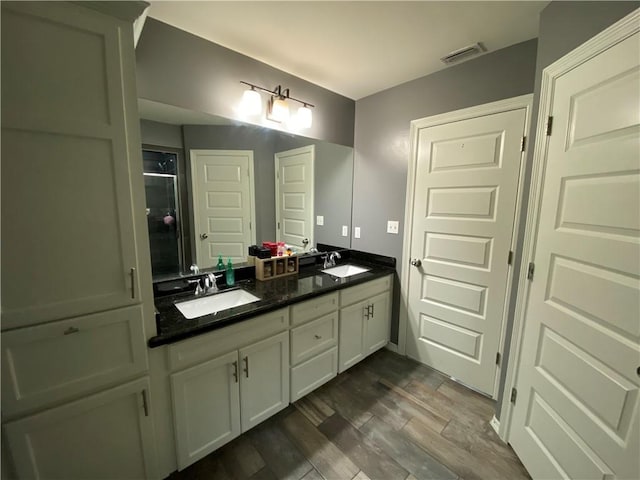 bathroom with hardwood / wood-style floors, vanity, and a shower with door