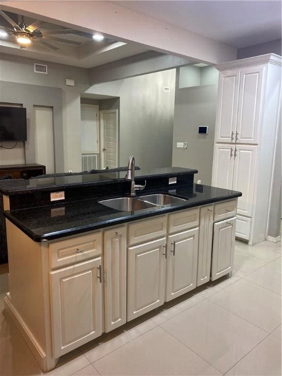 kitchen with a center island with sink, white cabinets, sink, ceiling fan, and light tile patterned floors