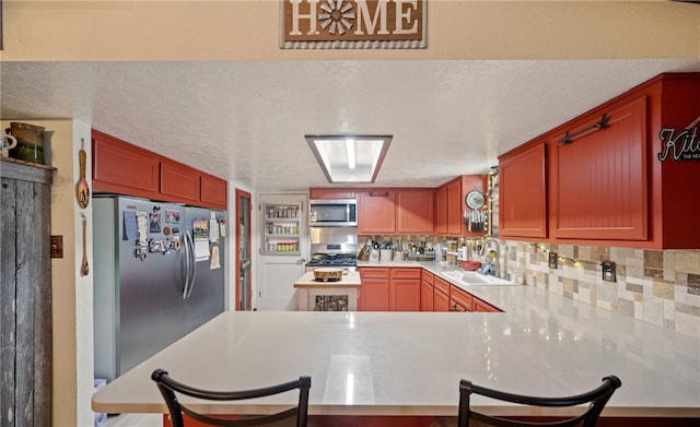 kitchen featuring a sink, a textured ceiling, tasteful backsplash, and stainless steel appliances