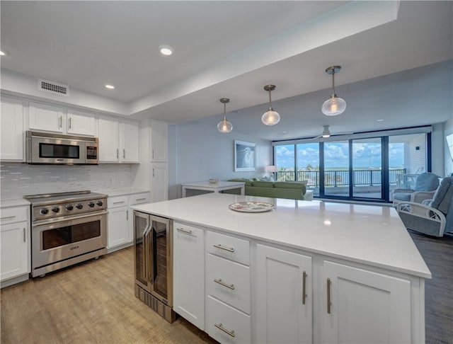 kitchen featuring white cabinetry, appliances with stainless steel finishes, decorative light fixtures, beverage cooler, and decorative backsplash