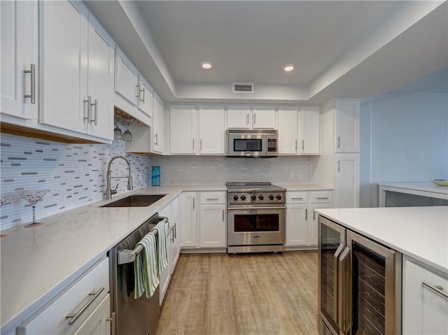 kitchen featuring stainless steel appliances, white cabinetry, sink, wine cooler, and decorative backsplash