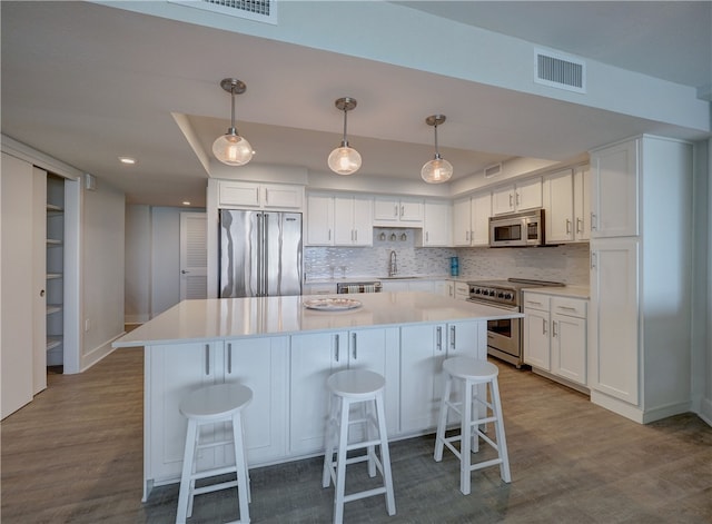 kitchen featuring a kitchen island, white cabinetry, a kitchen bar, and high end appliances