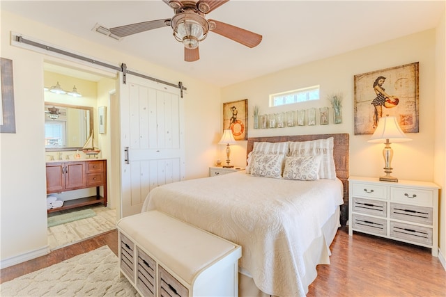 bedroom featuring a closet, a barn door, ceiling fan, and hardwood / wood-style floors