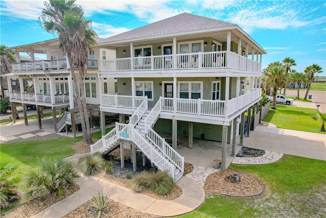 rear view of house with a lawn, a balcony, and covered porch