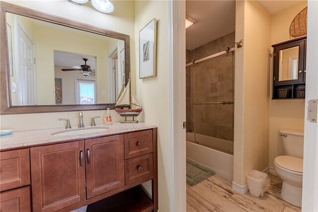 full bathroom with wood-type flooring, toilet, tiled shower / bath, vanity, and ceiling fan