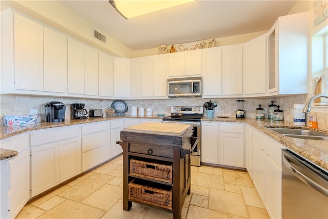 kitchen featuring stainless steel appliances, white cabinets, decorative backsplash, sink, and light stone countertops