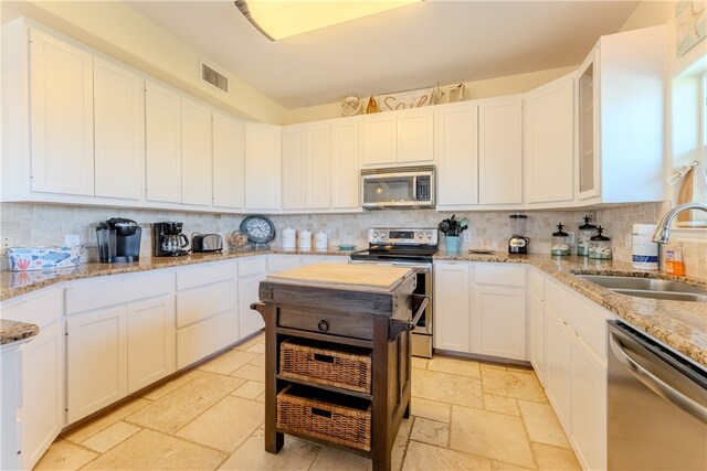 kitchen featuring stainless steel appliances, white cabinets, decorative backsplash, sink, and light stone countertops