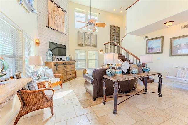 living room with a towering ceiling, ceiling fan, and a healthy amount of sunlight