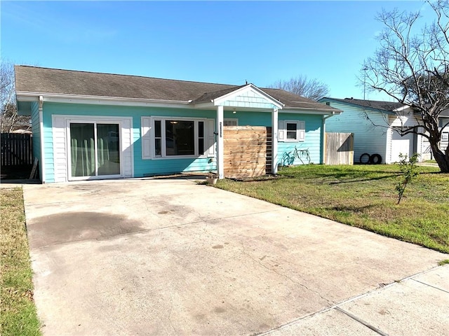 ranch-style home with concrete driveway, a front yard, and fence