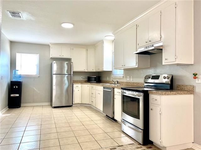 kitchen with visible vents, appliances with stainless steel finishes, a sink, under cabinet range hood, and baseboards