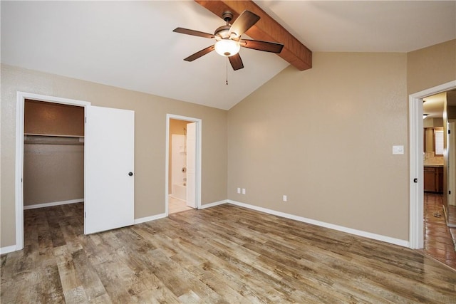 unfurnished bedroom with hardwood / wood-style flooring, a walk in closet, vaulted ceiling with beams, and a closet