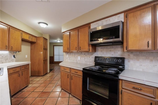 kitchen featuring tasteful backsplash, black electric range, and light tile patterned floors