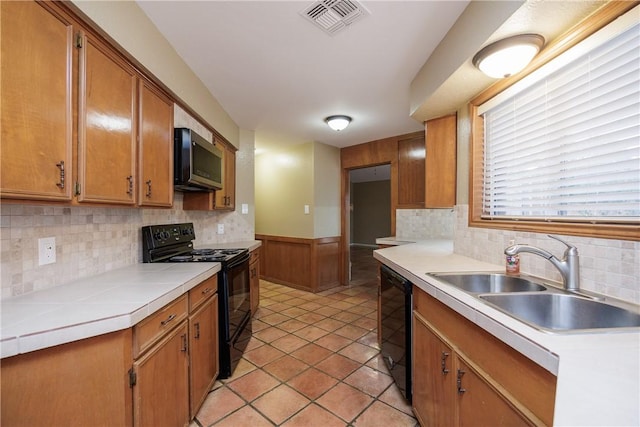 kitchen with sink, light tile patterned floors, backsplash, tile counters, and black appliances