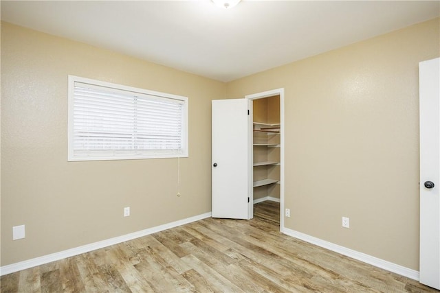 unfurnished bedroom featuring a spacious closet, light hardwood / wood-style flooring, and a closet