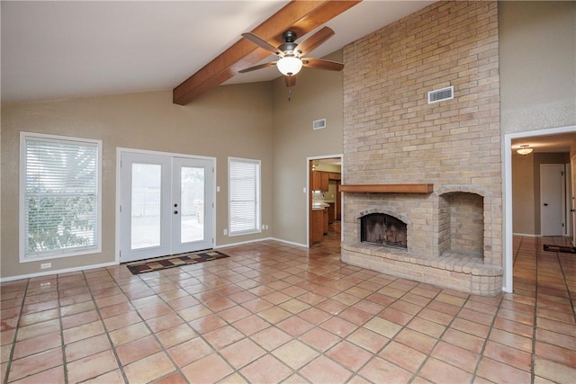 unfurnished living room with light tile patterned flooring, french doors, a brick fireplace, ceiling fan, and beam ceiling