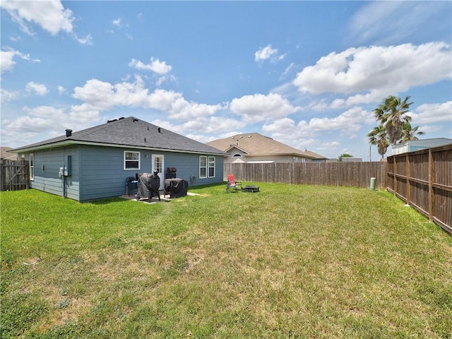 rear view of property featuring a fenced backyard and a lawn