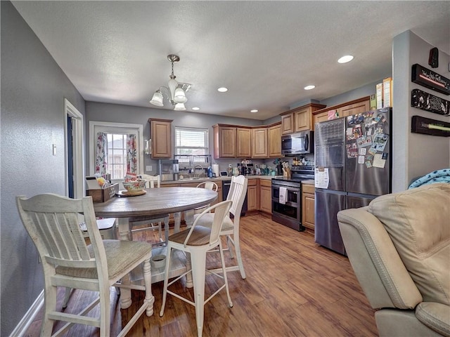 kitchen featuring a chandelier, light wood-type flooring, decorative light fixtures, appliances with stainless steel finishes, and recessed lighting