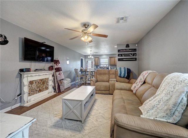 living area with baseboards, a ceiling fan, light wood finished floors, and visible vents
