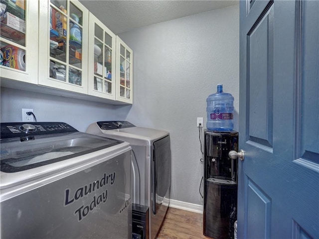 laundry room with cabinet space, wood finished floors, washing machine and clothes dryer, and baseboards