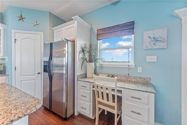 kitchen with dark wood-type flooring, white cabinets, light stone countertops, built in desk, and stainless steel fridge