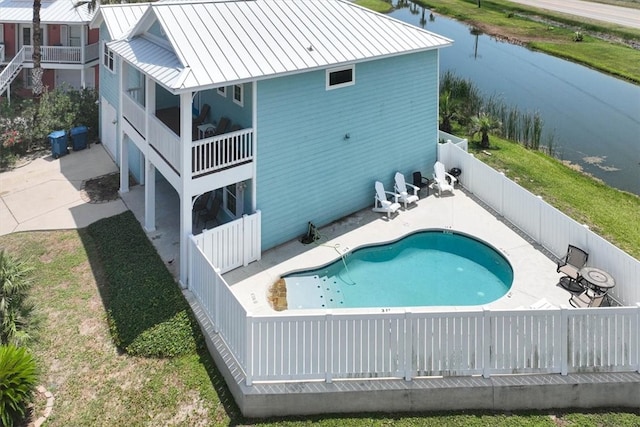 rear view of house featuring a fenced in pool, a patio, a water view, and a balcony