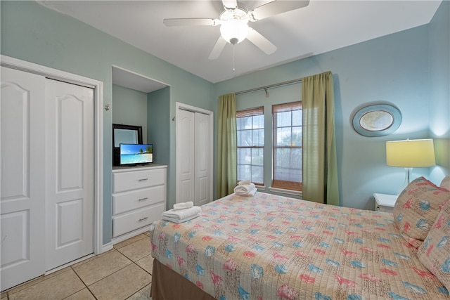 bedroom with light tile patterned flooring, two closets, and ceiling fan