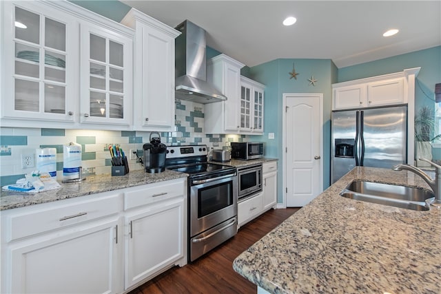 kitchen with white cabinets, appliances with stainless steel finishes, sink, and wall chimney range hood