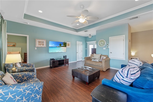 living room with dark wood-type flooring, a tray ceiling, ceiling fan, and crown molding