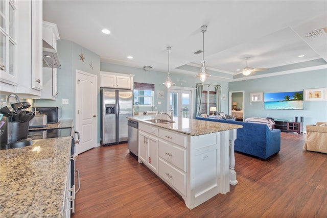 kitchen with a center island with sink, white cabinetry, appliances with stainless steel finishes, dark wood-type flooring, and pendant lighting