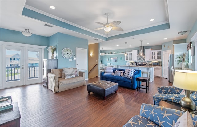 living room with ornamental molding, dark wood-type flooring, and a tray ceiling