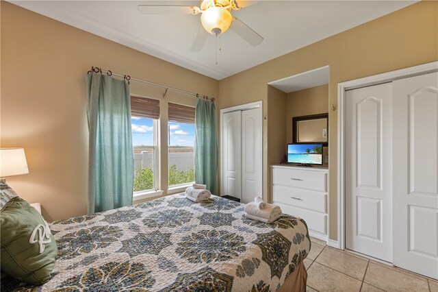 bedroom featuring multiple closets, light tile patterned floors, and ceiling fan