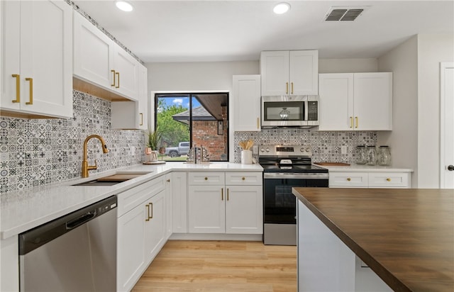 4530 Megal Dr, Corpus Christi, TX 78413 - kitchen featuring stainless steel appliances, a sink, butcher block countertops, white cabinetry, and light wood-style floors