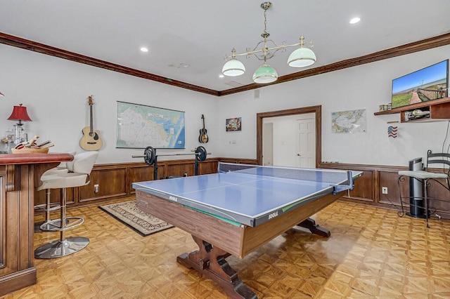 recreation room featuring light parquet floors, a chandelier, indoor bar, and ornamental molding