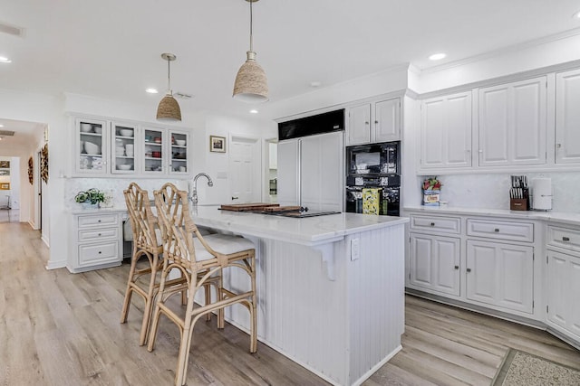 kitchen featuring black appliances, white cabinetry, and a kitchen island with sink