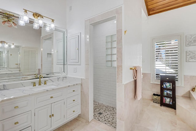 bathroom featuring tiled shower, tile patterned flooring, tile walls, and vanity