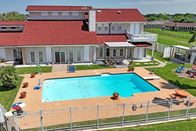 rear view of property with a lawn, a fenced in pool, and a patio