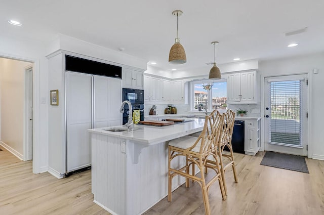 kitchen with white cabinetry, black appliances, a center island, and decorative light fixtures