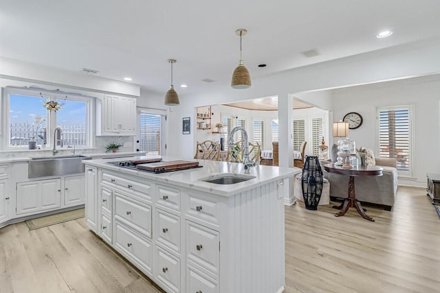 kitchen with a kitchen island with sink, a wealth of natural light, sink, and white cabinets