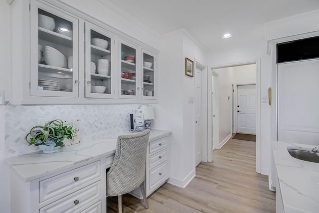 home office with ornamental molding, light hardwood / wood-style floors, built in desk, and sink