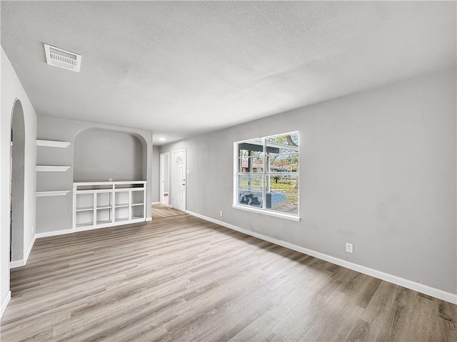 unfurnished living room featuring a textured ceiling and light wood-type flooring