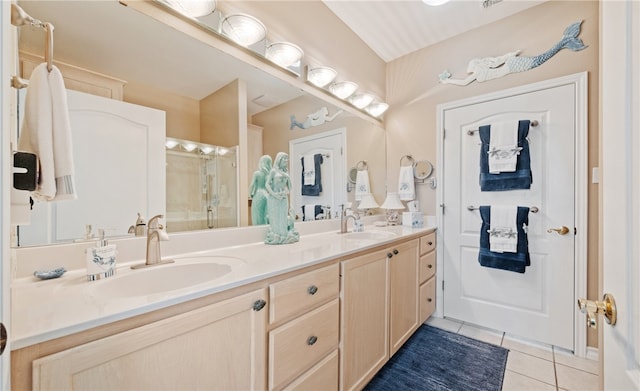 full bathroom featuring double vanity, a shower with door, a sink, and tile patterned floors