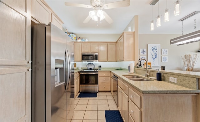 kitchen featuring light brown cabinetry, a peninsula, a sink, and stainless steel appliances