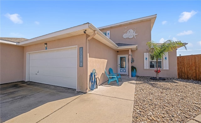 view of front facade featuring a garage, driveway, fence, and stucco siding