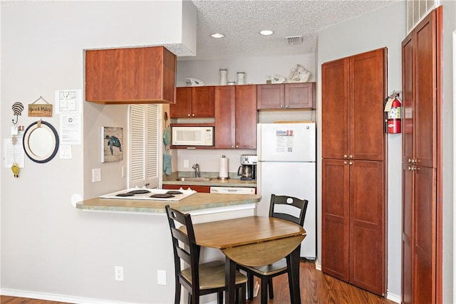 kitchen with white appliances, dark hardwood / wood-style flooring, sink, and a textured ceiling