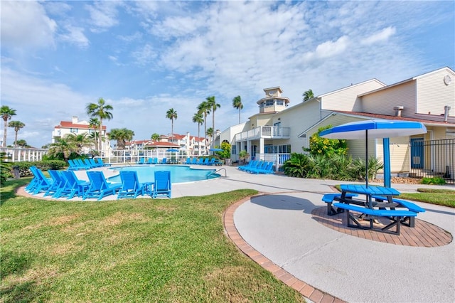 pool with a lawn, a patio, and fence