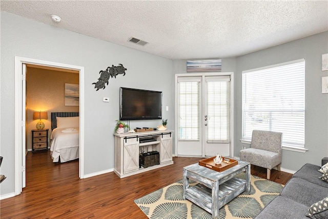 living room featuring a healthy amount of sunlight, dark wood-type flooring, and a textured ceiling