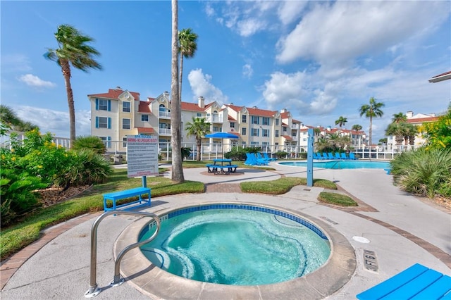 pool featuring a community hot tub and fence