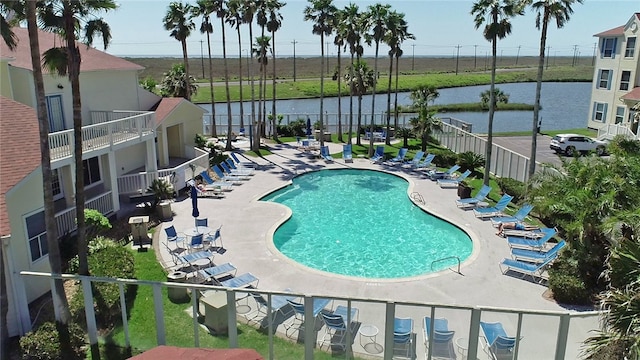 community pool featuring a patio area, a water view, and fence